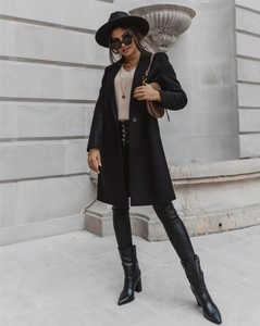Detail of long black wool coat showing premium fabric texture and classic lapel collar