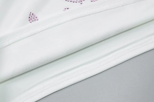 Detailed close-up of white fabric with pink rhinestones and double-needle stitching