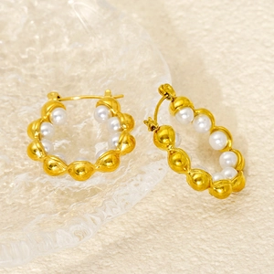 Detailed close-up of 18k gold hoop earrings with inset white pearls and latch closure