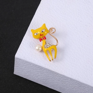 Detail of yellow enamel cat brooch with white pearl and rhinestone on leather display