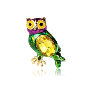 Detail of colorful owl brooch with inlaid yellow gemstones and purple enamel finish