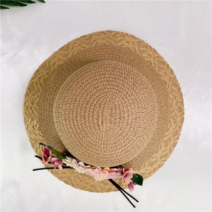 Close-up of woven straw sun hat with pink floral decoration and refined texture