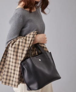 Minimalist black PU leather tote bag with silver buckle worn with a plaid coat