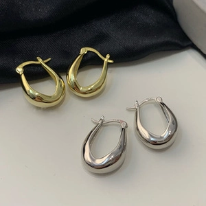 Detail of S925 sterling silver stamp on minimalist gold and silver U-shaped hoop earrings