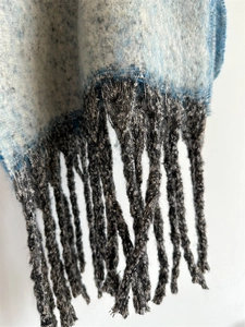 Close-up of the thick woven gradient scarf fabric with detailed dark grey fringe accents