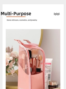Pink makeup brush organizer bag with mesh window shown on a vanity table