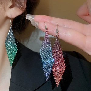 Gros plan de boucles d'oreilles losanges à franges serties de diamants en vert, bleu et brun