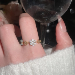 Detailed close-up of a delicate gold flower ring with zircons worn on a model finger