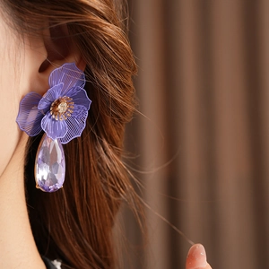 Detail of purple flower earrings with water drop crystal pendants on a female model