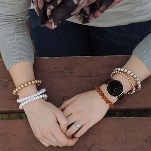 Close-up of stylish ladies quartz watch with brown leather strap and layered bracelets