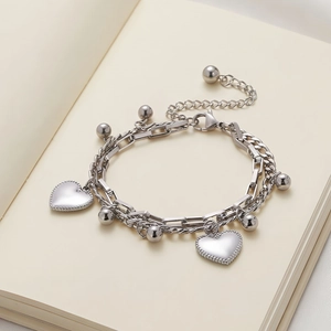 Close-up of double-layered silver heart bracelet with metal beads on a book background