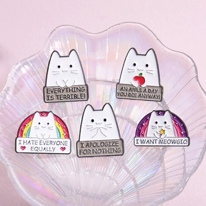 Set of five cute cartoon cat enamel pins with rainbow and heart motifs in a glass dish