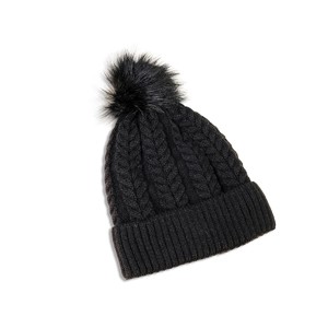 Detail of cable knit pattern and black faux fur pom-pom on a classic winter beanie