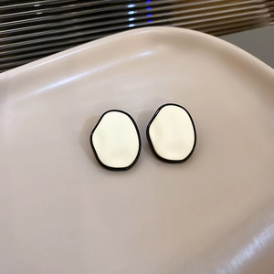 Gros plan détaillé de boucles d'oreilles carrées crème avec bordure noire contrastée
