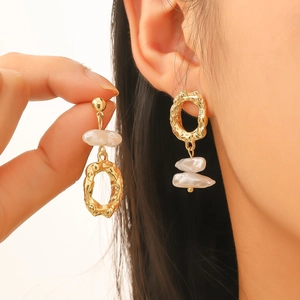 Minimalist asymmetric baroque pearl earrings in gold finish worn by a model