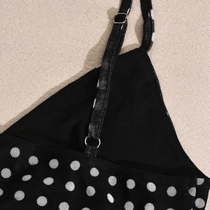 Detail of adjustable strap and silver buckle on black mesh polka dot crop top and skirt