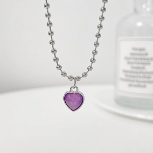 Macro shot of silver bead chain necklace featuring a purple heart-shaped marble pendant