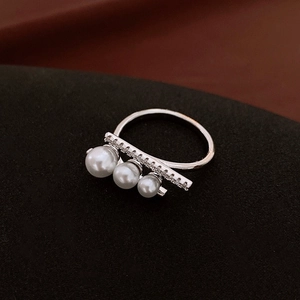 Close-up of zircon bar and three graduated white pearls on a silver open ring band