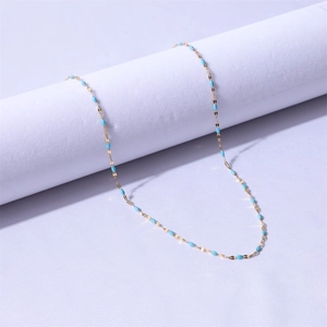 Detail of 18k gold plated stainless steel chain with turquoise enamel beads on purple fabric