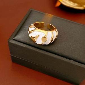 Detail of vintage gold-plated wide ring featuring white enamel wave textures on a gift box