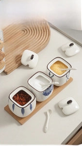 Detail view of Japanese ceramic seasoning jars with wooden tray and white spoons
