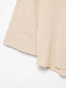 Gros plan détaillé sur la texture du lin et les coutures fines de la chemise beige