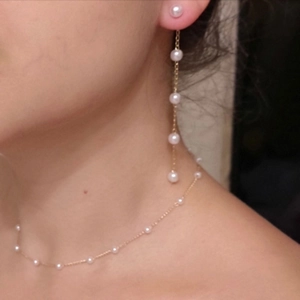 Detailed view of long pearl fringe earrings and matching necklace set on a model