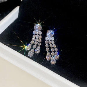 Detail of silver needle earrings with zircon chains showing sparkling starburst reflections