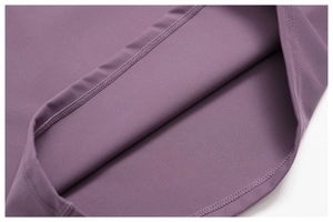 Détail de couture à double aiguille sur ourlet de tenue de yoga en tissu brossé violet