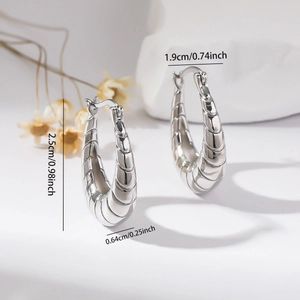 Macro view of silver crescent earrings with cocoon texture and precise size dimensions