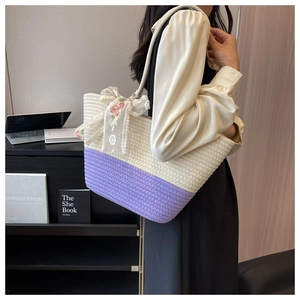 Detail of woven tote bag with purple accents and floral lace bow on shoulder strap