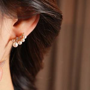 Close-up of elegant 18k gold plated pearl earrings with zircon inlay on model's ear