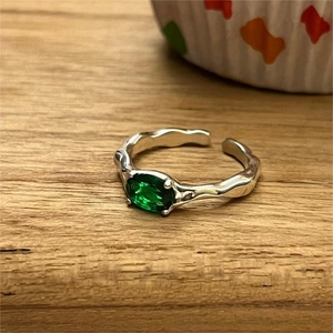 Detail of a 925 sterling silver ring with a green emerald gemstone on a wooden surface