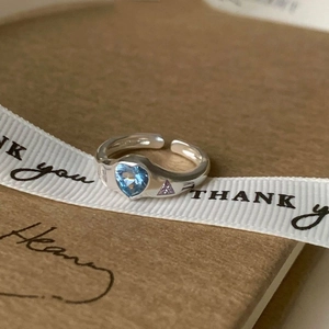 Detail of adjustable silver ring with blue heart stone and purple side crystals