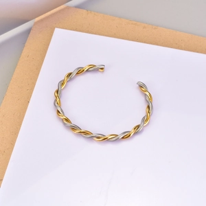 Detail of twisted cable cuff bracelet in gold and silver finish with flat metal end caps