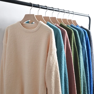 Close-up of plush knit sweaters in various colors hanging on a minimal display rack