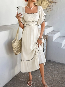 Detail of bohemian white dress showing black wavy trim and ruffled sleeve texture