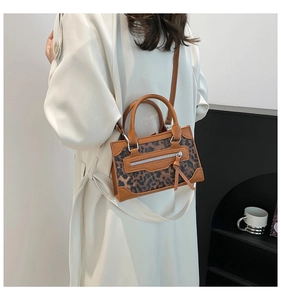 Bolso bandolera de leopardo con ribete de cuero marrón sobre un abrigo marfil