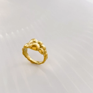 Macro shot of gold abstract fluid lava ring with unique bubble texture and metallic finish