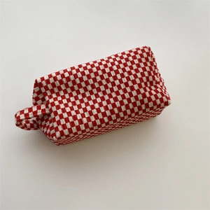 Detail view of red and white seersucker checkered cosmetic bag with textured fabric handle