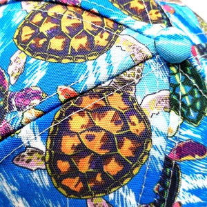 Makro-Detail des mehrfarbigen Schildkrötendrucks auf der hellblauen Twill-Stoff-Baseballkappe