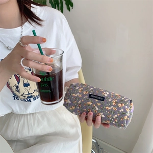 Close-up of purple floral corduroy pencil case held by a hand in a lifestyle setting