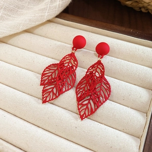 Detailed view of matte red hollow leaf tassel earrings displayed in a jewelry box