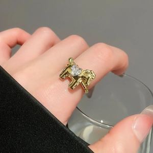 Detailed view of a gold horse ring with a sparkling heart-shaped zircon on a model's finger