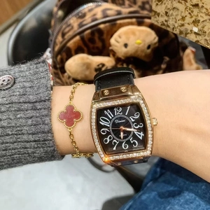 Close-up of a square gold lady's watch with black leather strap and diamond bezel