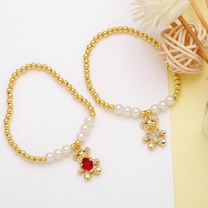 Close-up of pearl and copper bead bracelets featuring red and gold bear charms