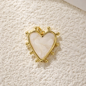 Detail of a heart-shaped pendant with gold metal frame and white pearlescent inlay