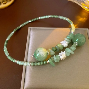 Dettaglio collana di perle verdi con decori floreali argentati su una scatola porta gioie