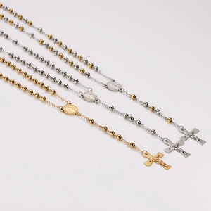 Three stainless steel rosary necklaces in gold, silver, and dual-tone with cross pendants