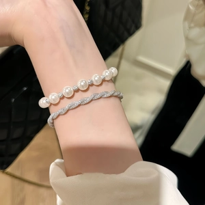 Detail of a pearl bracelet with diamond beads and a silver twisted rhinestone bangle